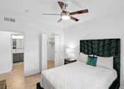 Thumbnail 27 of 45 - A bedroom with a bed, a ceiling fan, and a lamp.