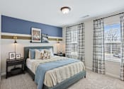 Thumbnail 26 of 37 - A bedroom with a bed, nightstand, and framed pictures on the wall.