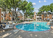 Thumbnail 29 of 38 - A swimming pool surrounded by trees and chairs in a residential area.