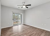 Thumbnail 5 of 45 - A room with a ceiling fan and sliding glass doors leading to a patio.