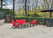 Thumbnail 28 of 45 - A patio with a red couch and a black umbrella.