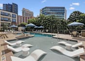 Thumbnail 3 of 26 - A pool with a modern design and white chairs around it.