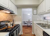 Thumbnail 12 of 29 - A kitchen with a black stove top oven and white cabinets.