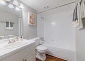 Thumbnail 17 of 29 - A white bathroom with a toilet, sink, and bathtub.