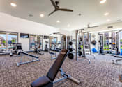 Thumbnail 21 of 32 - A spacious gym with a variety of equipment and a ceiling fan.