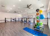 Thumbnail 23 of 32 - A gym with a blue mat on the floor and a variety of exercise equipment.