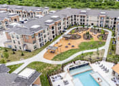 Thumbnail 30 of 32 - An aerial view of apartment buildings with a pool and a playground.
