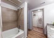 Thumbnail 12 of 32 - A bathroom with a white tub and a white chair in the closet.