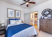 Thumbnail 29 of 29 - A bedroom with a blue bedspread and a ceiling fan.