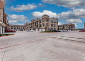 Thumbnail 32 of 32 - A parking lot in front of a large apartment complex.