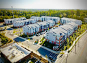 Thumbnail 26 of 27 - A large apartment complex with a parking lot in front.