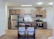 Thumbnail 23 of 27 - A kitchen with a table and chairs in the middle of the room.