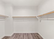 Thumbnail 11 of 24 - an empty room with white walls and wooden floors and a white closet with empty shelves