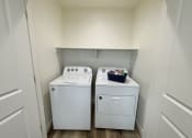 Thumbnail 29 of 46 - an empty laundry room with two washes and a dryer
