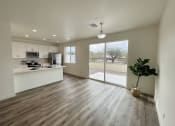 Thumbnail 24 of 46 - an empty living room with a kitchen and a sliding glass door