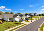 Thumbnail 2 of 33 - A residential street with houses on both sides and cars parked in front.