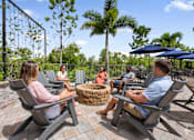 Thumbnail 59 of 59 - A group of people are sitting around a fire pit on a patio.