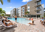 Thumbnail 54 of 59 - People are relaxing by the pool at a resort.