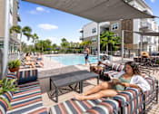 Thumbnail 5 of 59 - A woman is sitting on a striped couch by a pool.