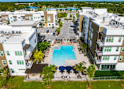 Thumbnail 4 of 59 - A swimming pool surrounded by apartment buildings and palm trees.
