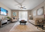 Thumbnail 13 of 35 - A living room with a flat screen TV mounted on the wall and a ceiling fan.