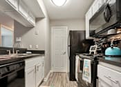 Thumbnail 19 of 35 - A kitchen with black appliances and white cabinets.