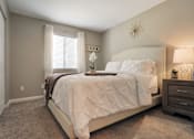 Thumbnail 24 of 35 - A bedroom with a large bed and a nightstand with a lamp.