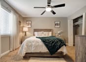 Thumbnail 21 of 35 - A bedroom with a bed, a ceiling fan, and a window with curtains.
