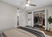 Thumbnail 5 of 30 - A bedroom with a bed, a ceiling fan, and a closet with clothes.