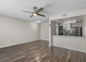 Thumbnail 12 of 30 - an empty living room with a ceiling fan and a kitchen