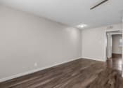 Thumbnail 15 of 30 - an empty living room with wood flooring and white walls