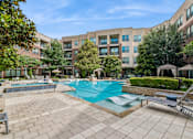 Thumbnail 16 of 30 - A large swimming pool surrounded by a brick patio and lounge chairs.