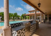 Thumbnail 13 of 33 - a covered patio with a swimming pool and a clubhouse in the background