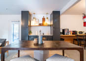 Thumbnail 38 of 44 - a living room with a wooden table and a kitchen with grey cabinets