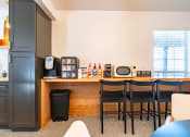 Thumbnail 40 of 44 - a kitchen with a bar with four chairs and a refrigerator and microwave