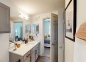Thumbnail 11 of 22 - a bathroom with a sink and a mirror and a door to a bedroom