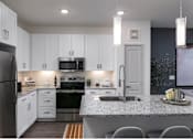 Thumbnail 1 of 47 - A modern kitchen with a granite countertop and stainless steel appliances.