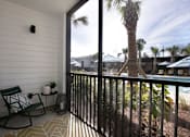 Thumbnail 16 of 47 - A balcony with a chair and a table with a plant on it.