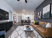 Thumbnail 9 of 47 - A modern living room with a brown leather couch and a black and white rug.