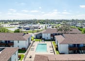 Thumbnail 13 of 14 - A view of apartment buildings with a pool in the foreground.