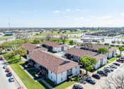Thumbnail 14 of 14 - A large white building with a red roof is surrounded by a parking lot.