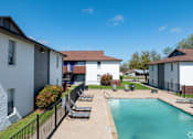 Thumbnail 12 of 14 - A swimming pool surrounded by a fence and chairs in a sunny day.