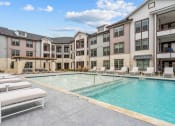 Thumbnail 9 of 47 - an apartment building with a swimming pool and lounge chairs