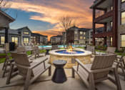 Thumbnail 12 of 47 - an outdoor patio with a fire pit and chairs at dusk