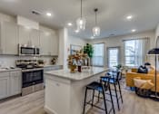 Thumbnail 15 of 24 - A modern kitchen with a large island and a dining area.