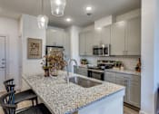 Thumbnail 16 of 24 - A kitchen with a granite countertop and a sink.