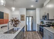 Thumbnail 14 of 24 - A modern kitchen with a stainless steel refrigerator and a wooden floor.