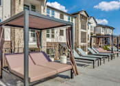Thumbnail 11 of 24 - A row of sun loungers are set up in front of apartment buildings.