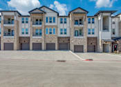 Thumbnail 5 of 24 - A large, empty parking lot in front of a multi-story apartment building.
