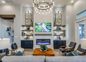 Thumbnail 1 of 24 - A living room with a large flat screen TV mounted on the wall above a fireplace.